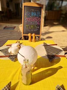 a table with a yellow table cloth with a sign and a bird on it at Samlee's Garden in Pakse