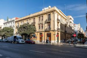 un gran edificio amarillo en una calle de la ciudad con coches en Premium Suite by the Turia River 4, en Valencia