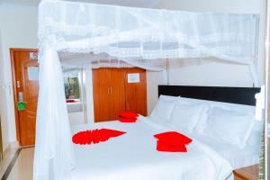a bedroom with a white bed with red pillows on it at Five to Five Hotel in Kigali