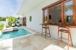 a swimming pool in a house with a bar and chairs at Salthouse Villa Uluwatu in Uluwatu
