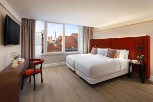 a bedroom with a large white bed and a window at NH Collection Gent in Ghent