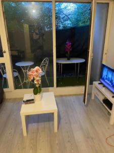 a living room with a vase of flowers on a table at Magnifique Studio entier en RDC in Les Ulis