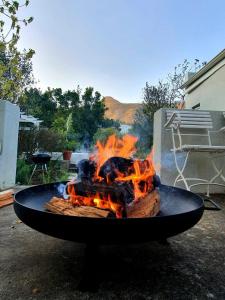 a fire pit with flames in a yard at Charming Rose Cottage in Greyton