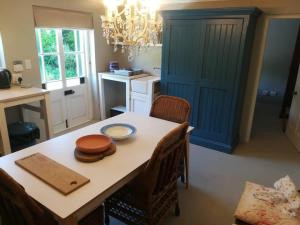 a kitchen with a table with chairs and a chandelier at Charming Rose Cottage in Greyton