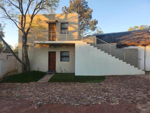 a white house with a staircase in front of it at Okoli's Place in Sandown