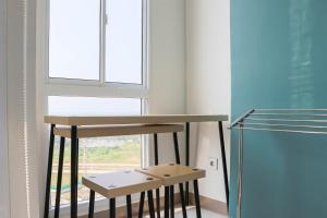 a table and two stools in a room with a window at Best Deal and Comfort Studio Tokyo Riverside PIK 2 Apartment By Travelio in Rawalembang +18 photos