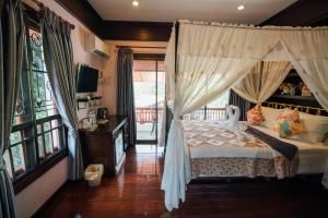 Un dormitorio con una cama con dosel y un balcón. en Ban Thong U, The Landmark, en Chiang Mai 23 fotos más