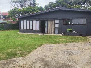 a small black house with a grass yard at 10 on Cane Street in East London