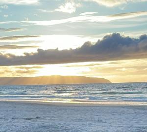 a beach with the sun setting on the ocean at Golfandbeach in Castlerock
