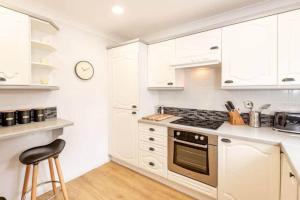 a kitchen with white cabinets and a stove top oven at Abbey Villa - No 5 in St. Andrews +11 photos