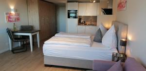 a small bedroom with a bed and a desk and a table at Hanseatenhaus in Westerland (Sylt)