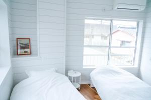a white bedroom with two beds and a window at Kametsu Surf House in Kametsu