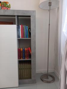 a book shelf with books and a floor lamp at La Casa di Gio ed Eli in Voghera