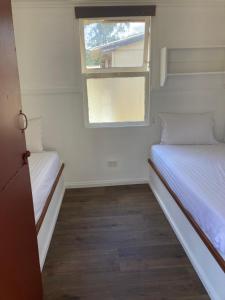 two beds in a small room with a window at Bright Cabin Park in Bright