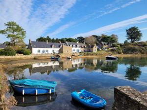 a house on the shore of a lake with boats in the water at Nouelig - A 150m de la plage de la Ria in Plouhinec