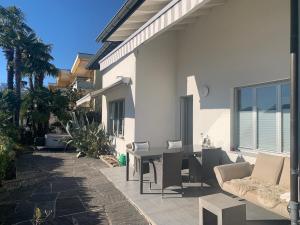 a patio with a table and chairs and a building at Casa Helios - traumhafte Seesicht, Jacuzzi, Sauna in Orselina +9 photos