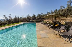 a swimming pool with chairs and an umbrella at Luxury Villa Acquaviva Firenze in Montauto