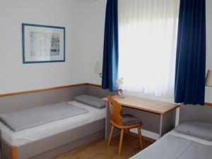 Cette chambre comprend deux lits, un bureau et une table. dans l'établissement Ferienhaus Nr 70, Kategorie Komfort, Feriendorf Hochbergle, Allgäu, à Bichel 8 autres photos