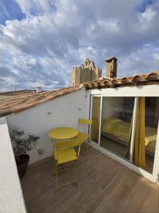 a yellow table and chairs on a balcony with a bed at Maison de ville sur 2 niveaux - 2 chambres - terrasse tropézienne in Saintes-Maries-de-la-Mer