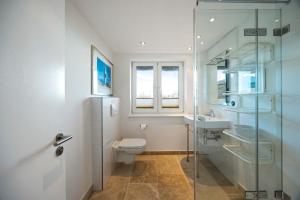 a bathroom with a toilet and a glass shower at Haus Sonnenland in Hörnum +21 photos