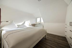 a white bedroom with a bed and a window at Haus Sonnenland in Hörnum