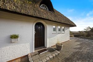 a white brick building with a thatched roof at Haus Sonnenland in Hörnum