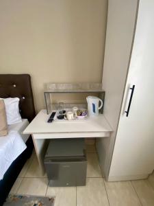 a small white desk with cups on it next to a bed at Mosas Home in Serowe