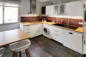 a kitchen with white cabinets and a sink and a table at Terrace Caluire in Caluire-et-Cuire