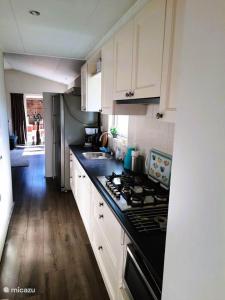 a kitchen with white cabinets and a stove top oven at Veluwe Happy Together in Epe +8 photos