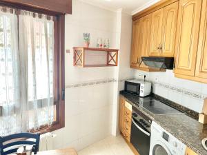 een keuken met een spoelbak en een magnetron bij Apartamento Cimadevilla 22 in Gijón
