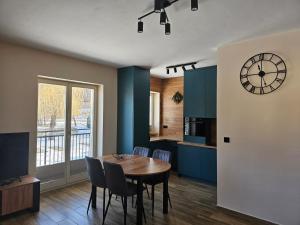 a kitchen and dining room with a table and a clock at Apartament Astra - Bliżej Zdroju in Polanica-Zdrój