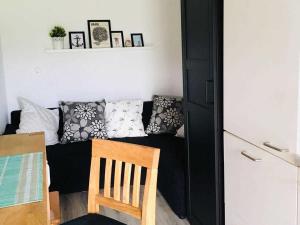 - un salon avec un canapé noir et des oreillers dans l'établissement Meedehof Moorhausen, WH Ziegenstall, à Varel