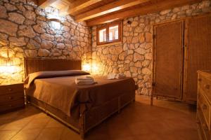 a bedroom with a bed and a stone wall at Dammuso Ignazio in Lampedusa