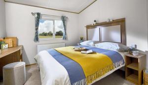 a bedroom with a large bed with a yellow and blue blanket at WH - Smugglers Cove 02 in Aberaeron