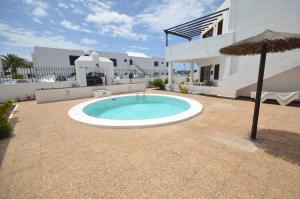 a pool in the middle of a patio with an umbrella at Sea Carnation Well Located, Pool & Terrace in Los Pocillos