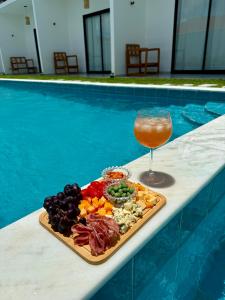 a tray of food and a drink next to a pool at Yahweh Hotel in São Miguel do Gostoso