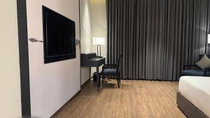 a hotel room with a bed and a desk and a television at The Borgo in Ludhiana
