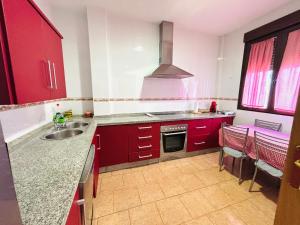 Una cocina con gabinetes rojos y un fregadero. en La Casa del Cuco, en Almodóvar del Río