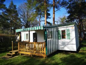 a small white house with a porch on the grass at Mobil Home 4 pers proche Puy du Fou et Montaigu (Vendée 85) in La Boissière-de-Montaigu