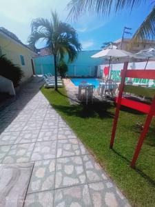 a patio with chairs and an umbrella next to a pool at Pousada Maceio Inn in Maceió