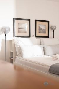 une chambre avec un lit blanc avec deux tableaux au mur dans l'établissement Functional 3city Apartment in Sopot with Parking by Noclegi Renters, à Sopot