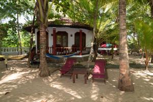 a house with a hammock in the middle of trees at Patini Bungalows - Beach Garden in Tangalle