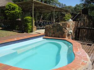 a swimming pool in a yard with a stone wall at Amatava Lodge in Mokopane