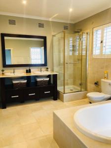 a bathroom with a shower and a toilet and a sink at Coral Tides -18 sleeper Beach house in Port Shepstone