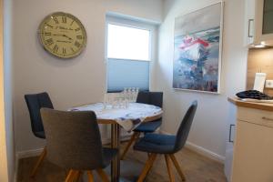 a dining room with a table and a clock on the wall at Deichnähe A in Norden +10 photos