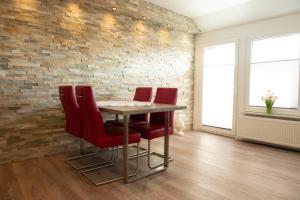 a dining room with red chairs and a brick wall at Clipper in Norden