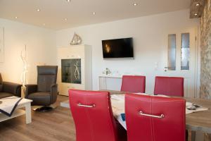 a dining room with a table and red chairs at Clipper in Norden