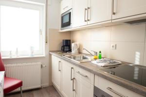 a kitchen with white cabinets and a sink and a window at Clipper in Norden