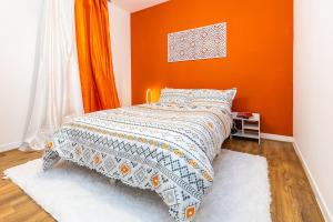 a bedroom with a bed with an orange wall at jaysapartment III in Aberdeen