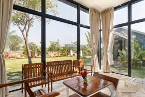 a living room with large windows and a table at TheSunlitHaven Pool GlassRooms Lawn in Raigīr